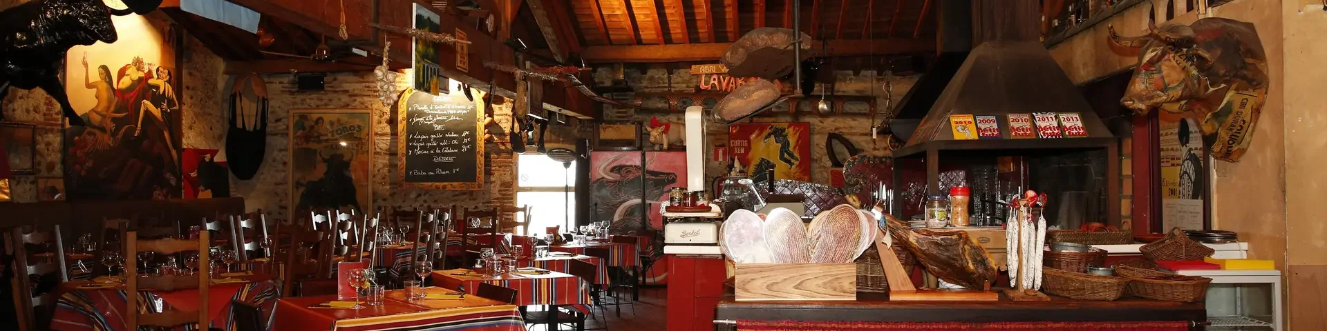 Salle de restaurant décorée avec des tables dressées et des éléments rustiques aux murs.