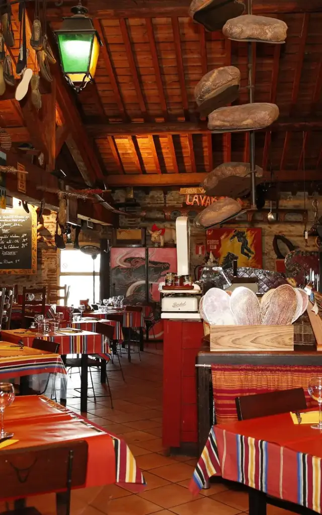 Salle de restaurant décorée avec des tables dressées et des éléments rustiques aux murs.