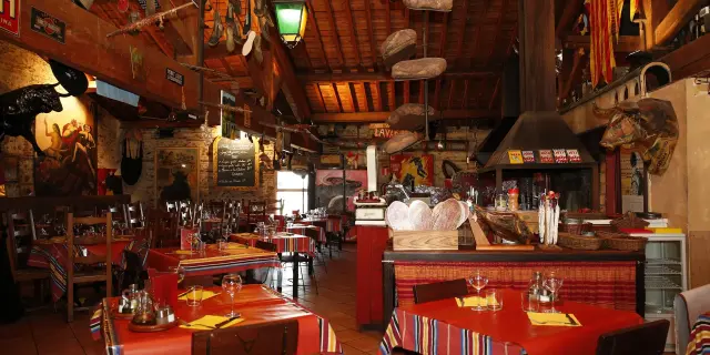Salle de restaurant décorée avec des tables dressées et des éléments rustiques aux murs.