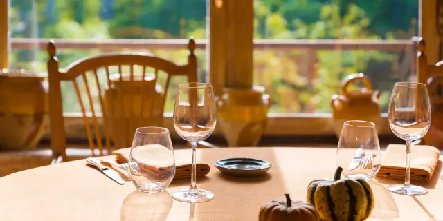 Table dressée avec verres et couverts devant une fenêtre donnant sur un jardin.