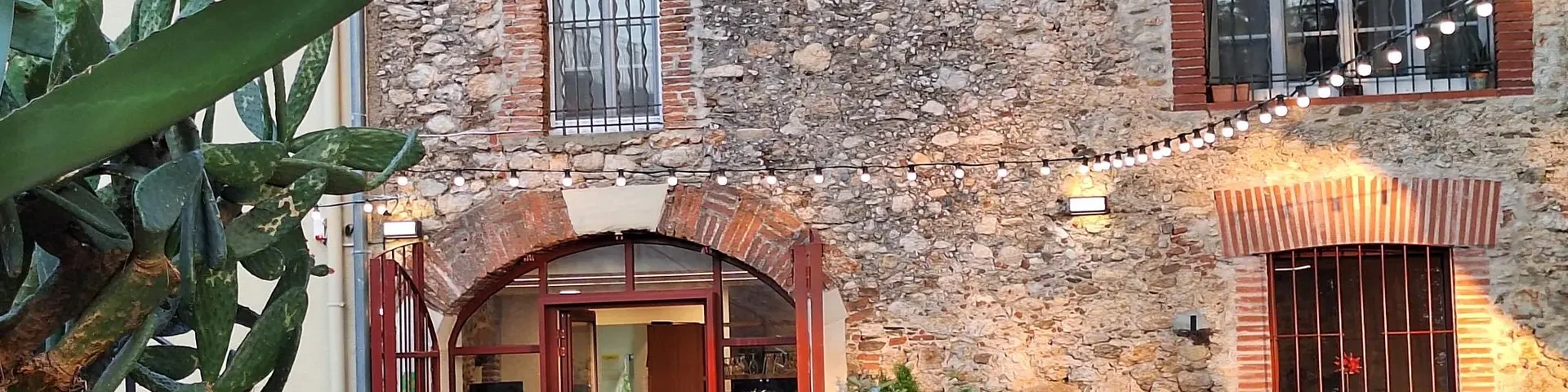 Façade en pierre du Relais de la Massane avec terrasse extérieure illuminée.