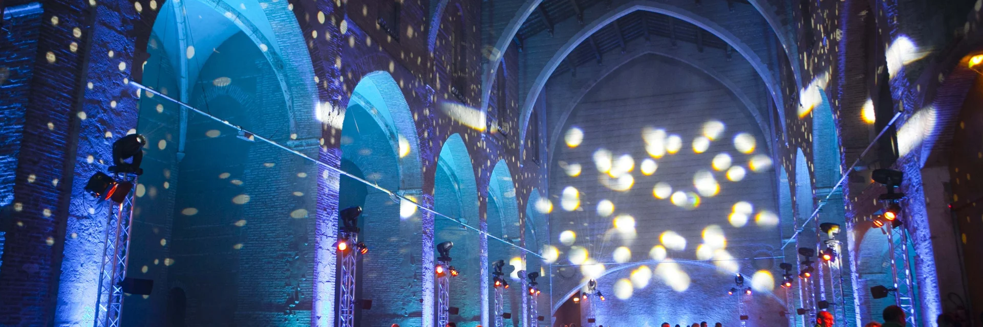 Dîner de gala dans la chapelle Saint-Dominique à Perpignan, éclairée de lumières bleues et dorées projetées sur les voûtes gothiques en brique.