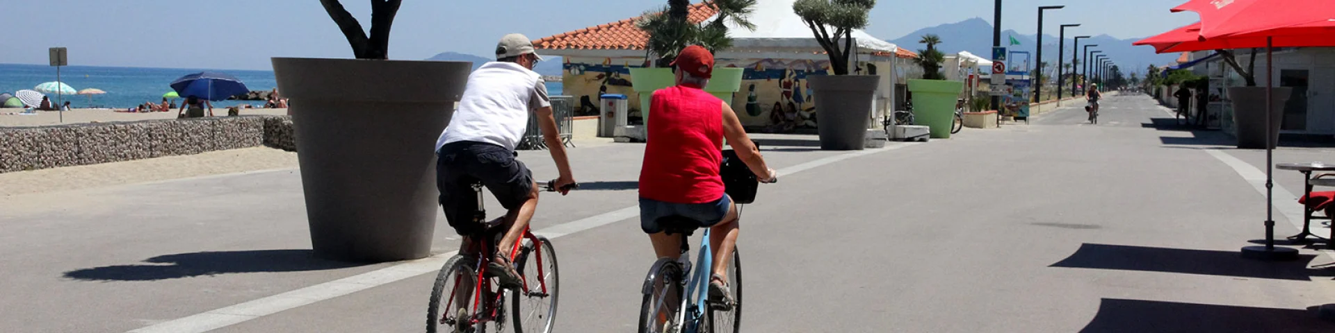 Deux cyclistes roulent sur une promenade aménagée en bord de mer.