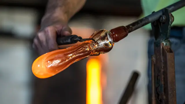 Gros plan sur une pièce de verre en fusion façonnée par un artisan verrier.