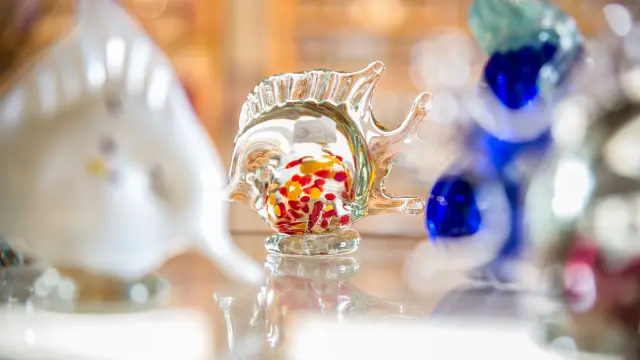 Petit poisson en verre soufflé coloré exposé sur une étagère.