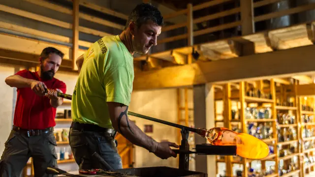 Souffleur de verre façonnant une pièce incandescente dans son atelier.