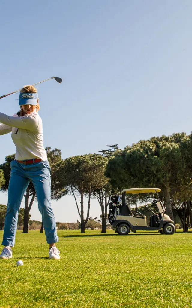 Golfeuse en plein swing sur le green du golf de Saint-Cyprien, sous un ciel bleu.