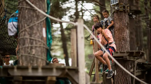 Enfant accroché à une tyrolienne sur un parcours d’accrobranche à Matemale.