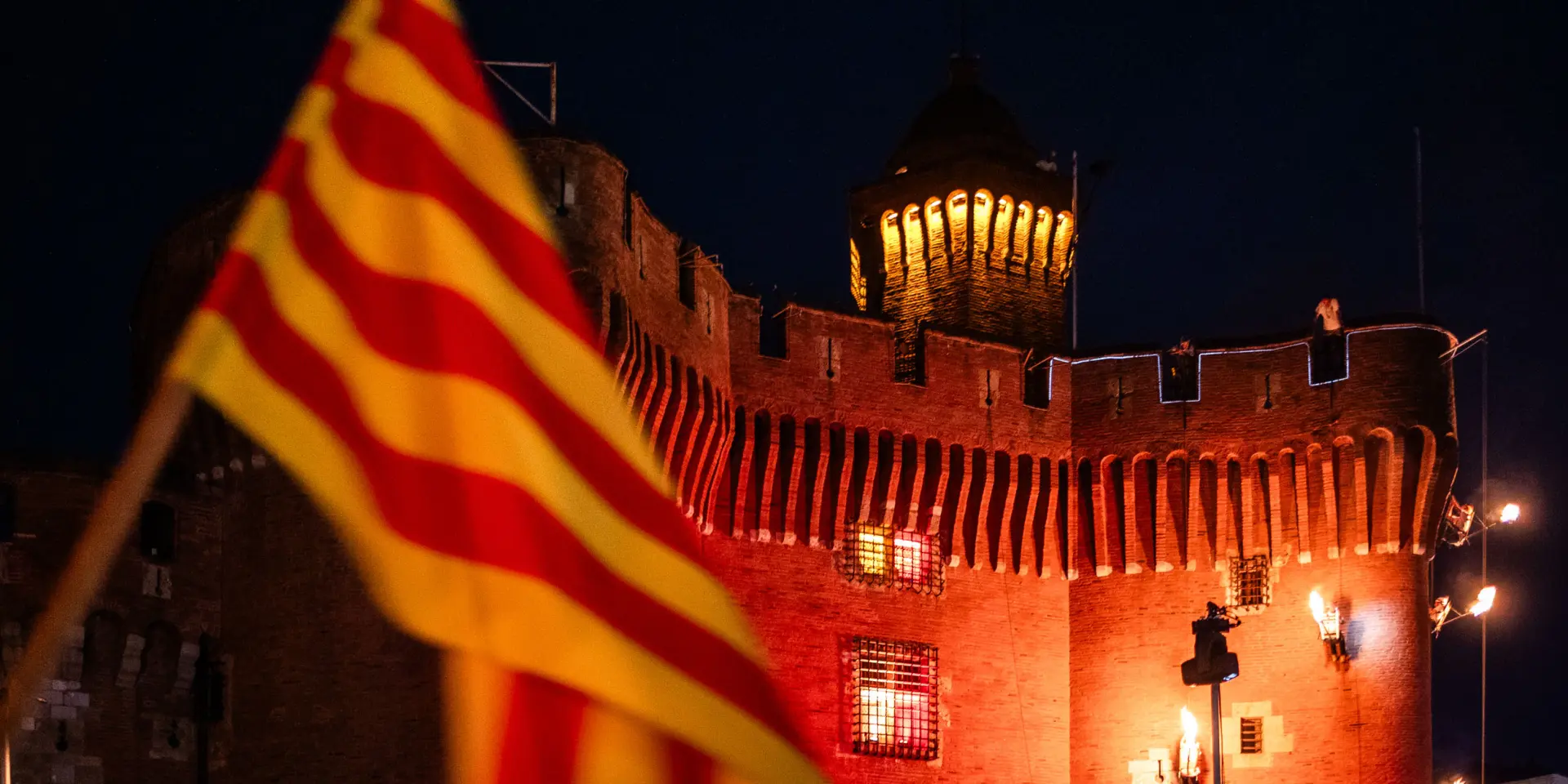 Grimpeurs escaladant le Castillet avec la flamme du Canigo dans leur dos pour embraser la derniere vasque du sommet du Castillet avec drapeau catalan sang et or depuis la Place de la Victoire a Perpignan dans le departement des Pyrenees-Orientales dans le Sud de la France le 23 juin 2026. Chaque annee la veille de la Saint Jean, la flamme eternelle des Catalans descend du Canigo pour allumer tous les villages de Catalogne avant de finir le parcours de cette tradition et ce patrimoine a Perpignan ou elle enflamme le Castillet, symbole de la ville.