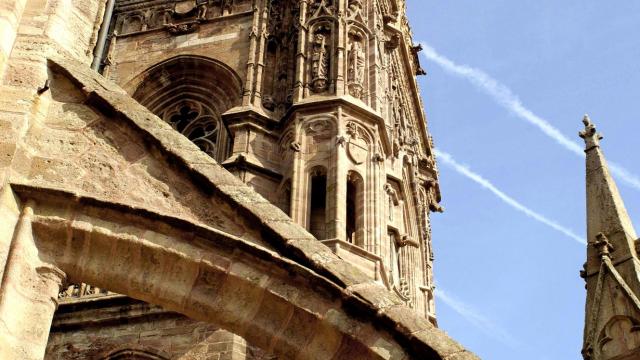 Vue du clocher de la cathédrale de Rodez depuis le toit terrasse, sous une arche avec un ciel bleu