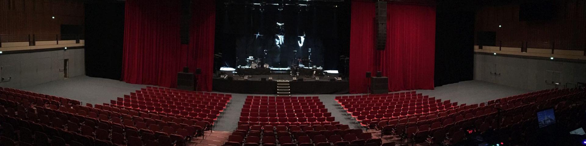 Salle de spectacle de l'Amphithéâtre vide avec des gradins et rideaux rouge