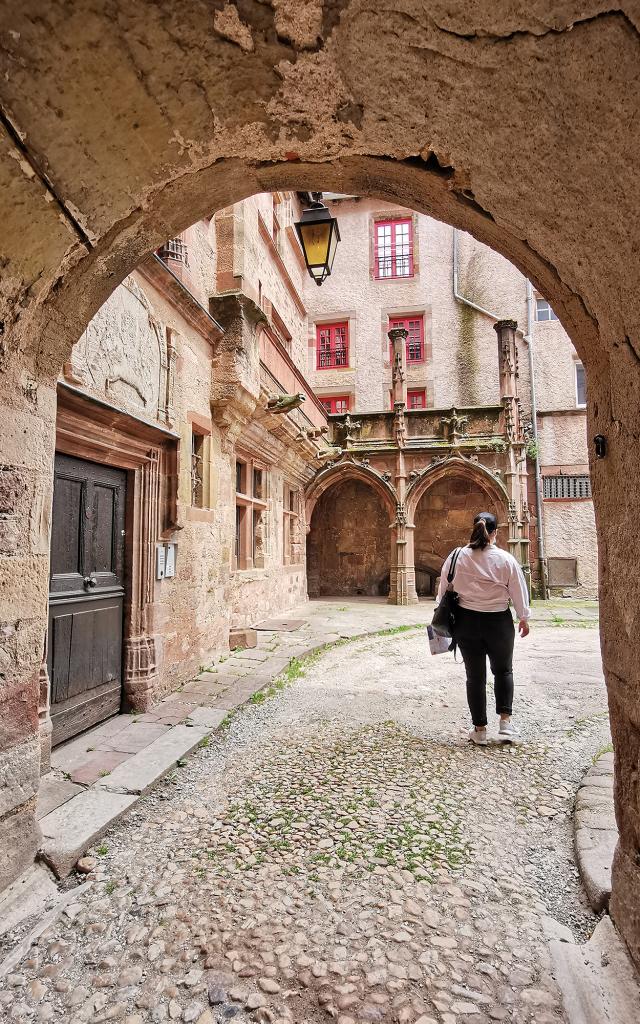 Personne qui traverse le passage voûté en pierre de la Maison Benoît pour accéder à une cour intérieure