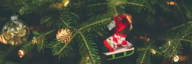 Boules de Noël accrochées aux branches d'un sapin, ainsi qu'une figurine animalière sur une luge