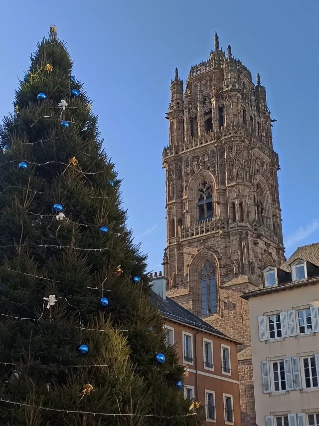Sapin géant décoré pour Noël devant le clocher de la cathédrale, sous un ciel bleu