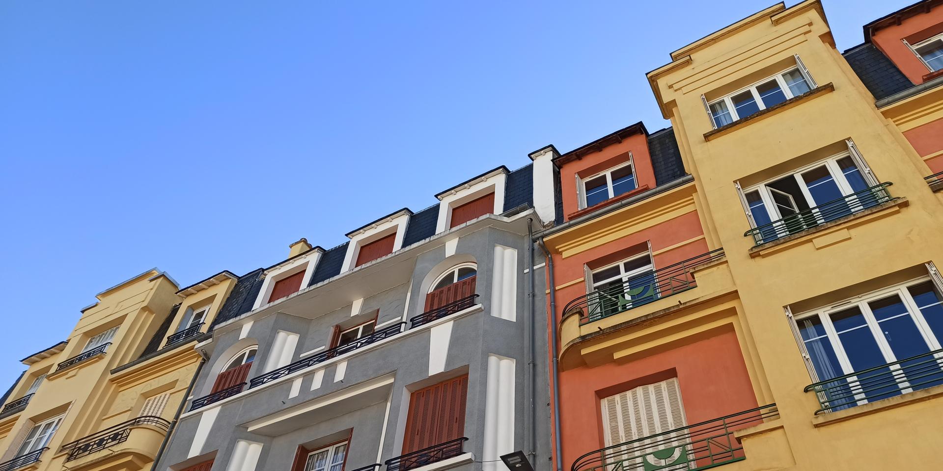 Immeubles Art Déco colorés aux balustrades en fer, sous un ciel bleu