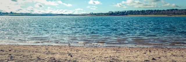 Plage au bord du lac de Pareloup, avec une bouée d'amarrage jaune sur le sable