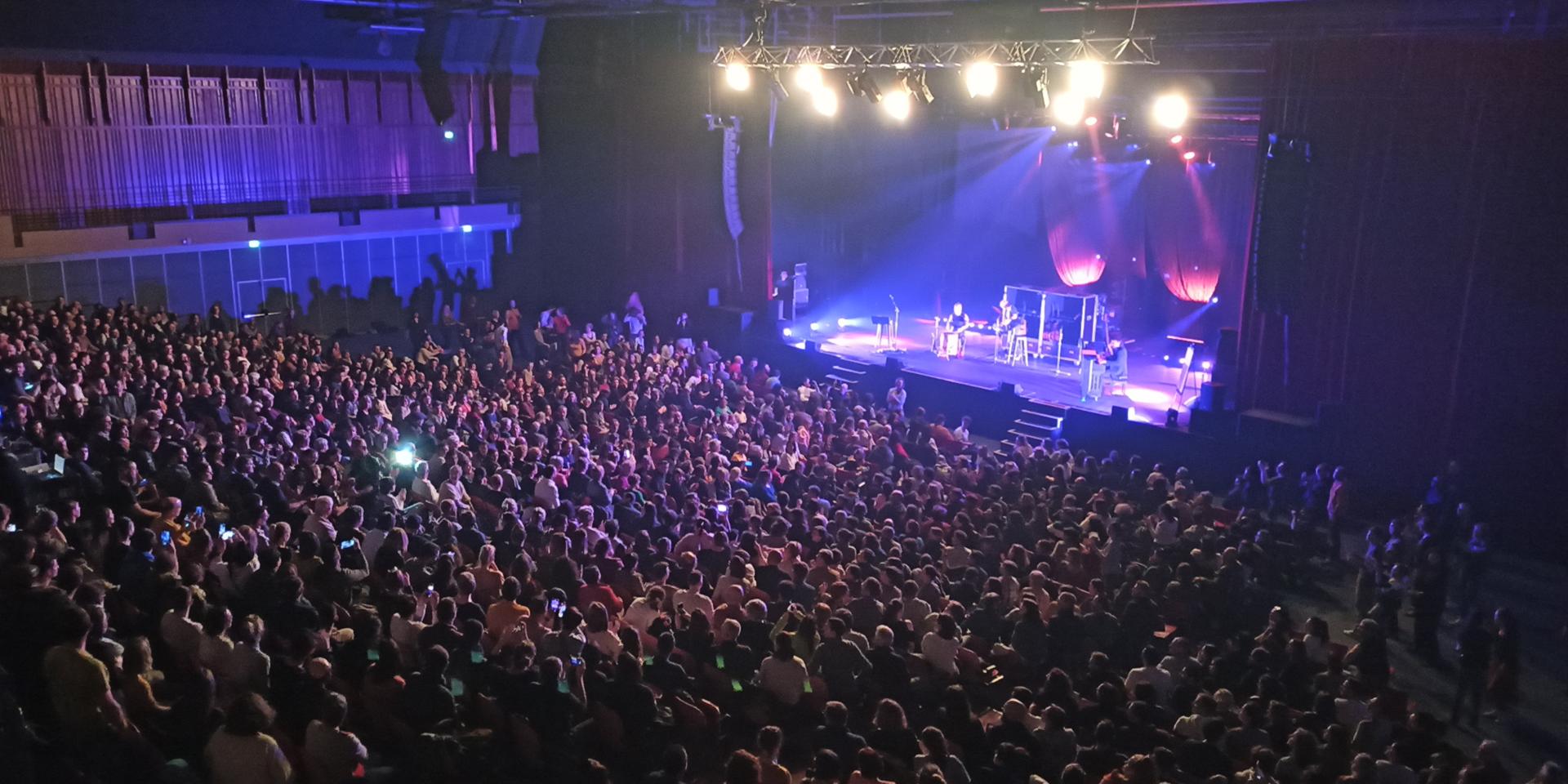 Foule de personnes dans la salle de spectacle de l'Amphithéâtre à Rodez, devant une scène avec des artistes