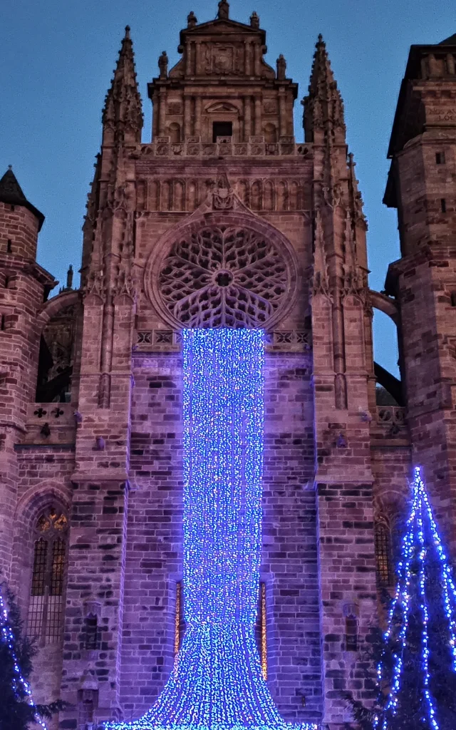 Pour Noël, à la nuit tombée, une cascade de lumière bleue descend de la rosace de la cathédrale vers la place en contrebas, au milieu de sapins illuminés