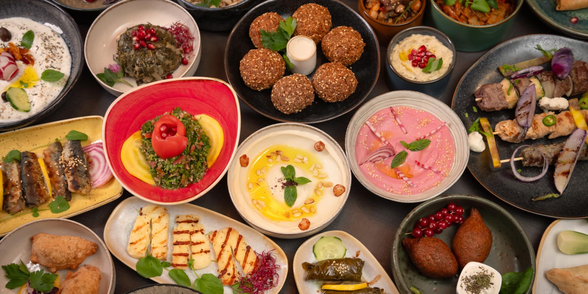 Festin avec multitude de mezzés libanais dans des assiettes individuelles : houmous, boulettes kebbe, feuilles de vigne, ...