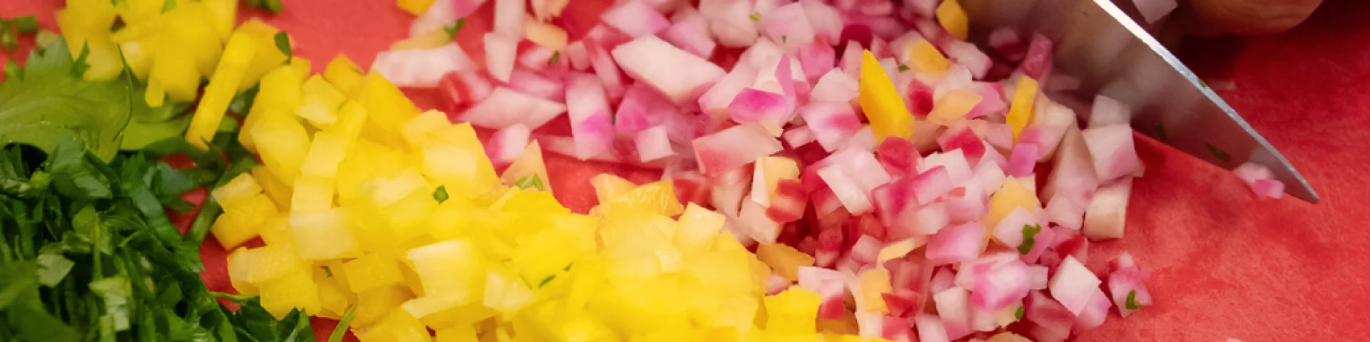 Mains d'un cuisinier découpant finement des condiments au couteau