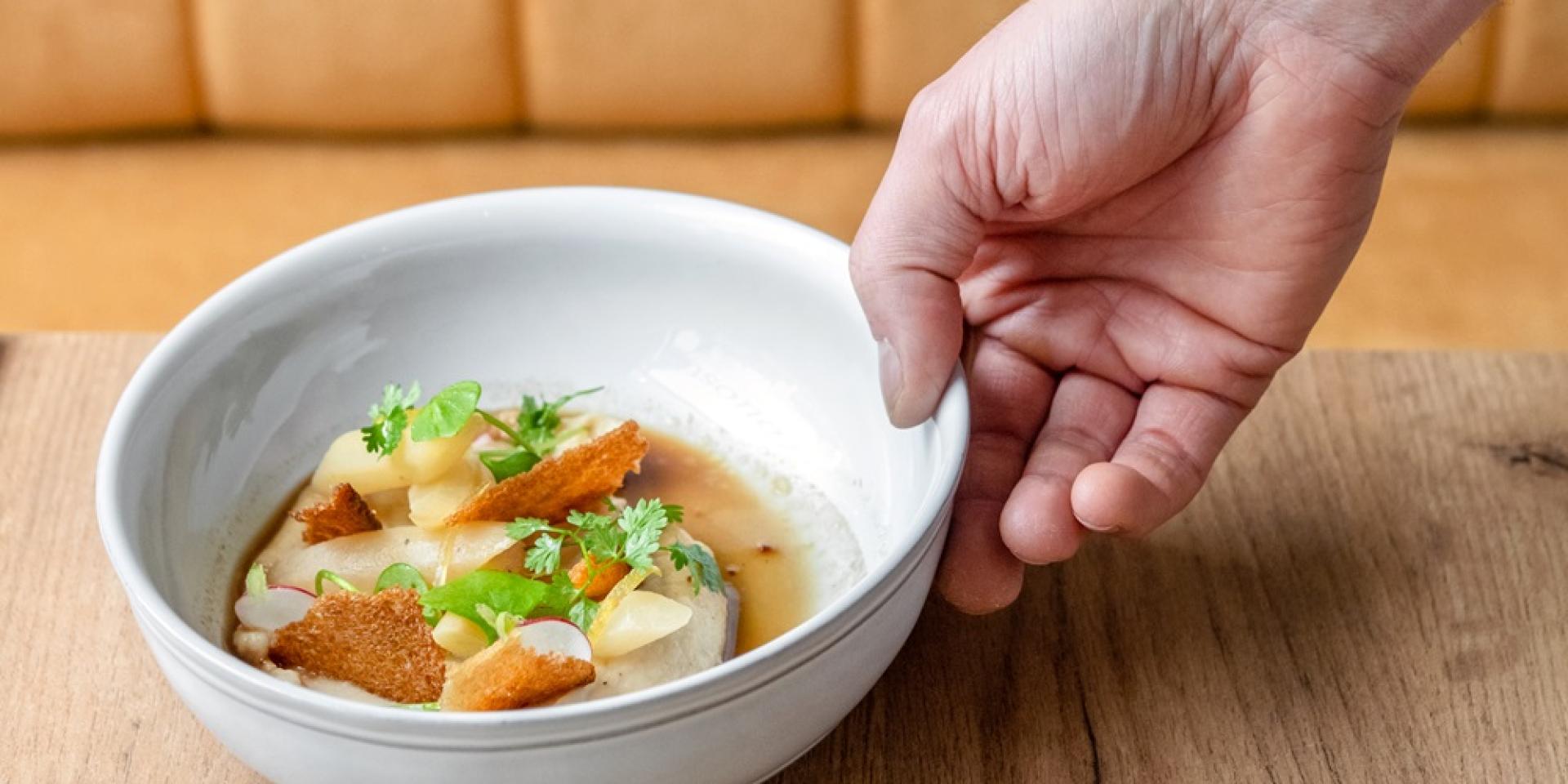 Plat cuisiné par Touosto dans une assiette blanche, tenue par une main