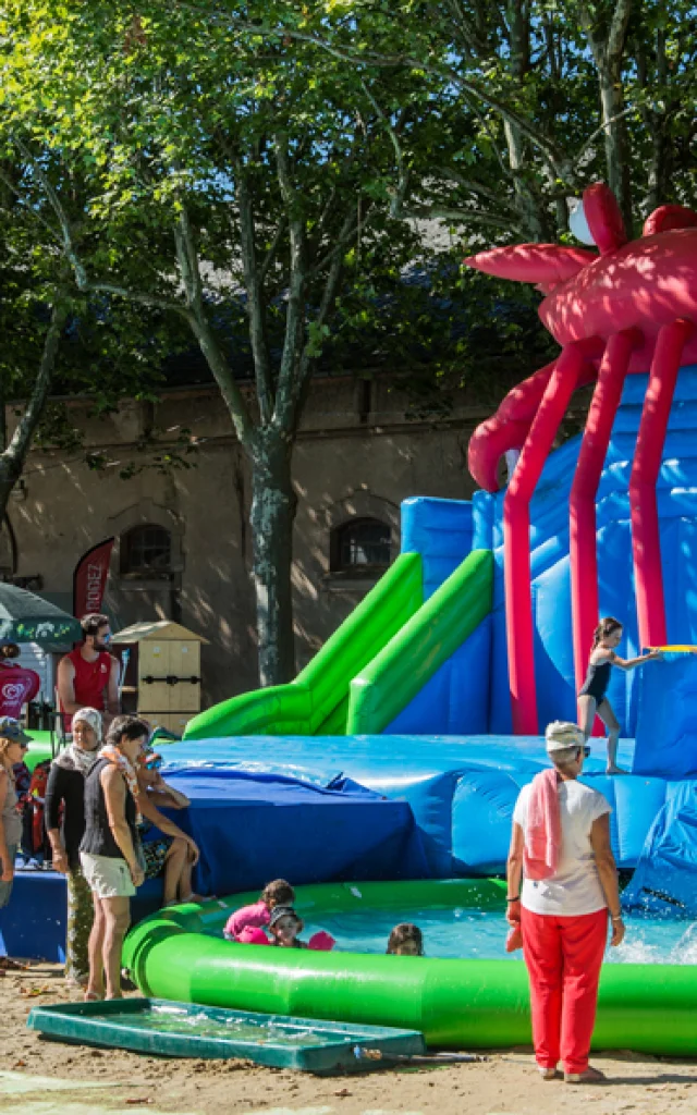 Parents devant des jeux gonflables et des jeux d'eau où s'amusent leurs enfants