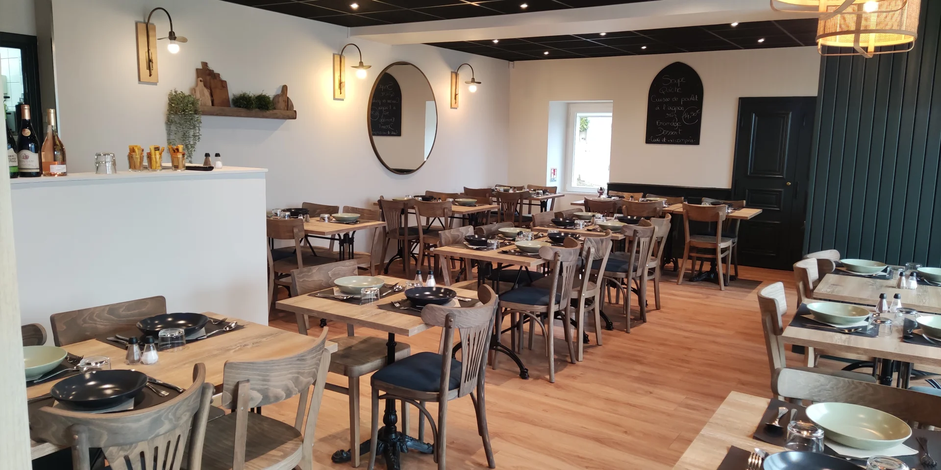 Salle de restaurant de l'hôtel Le Bistrot, avec ses tables et chaises en bois dans une ambiance simple et moderne