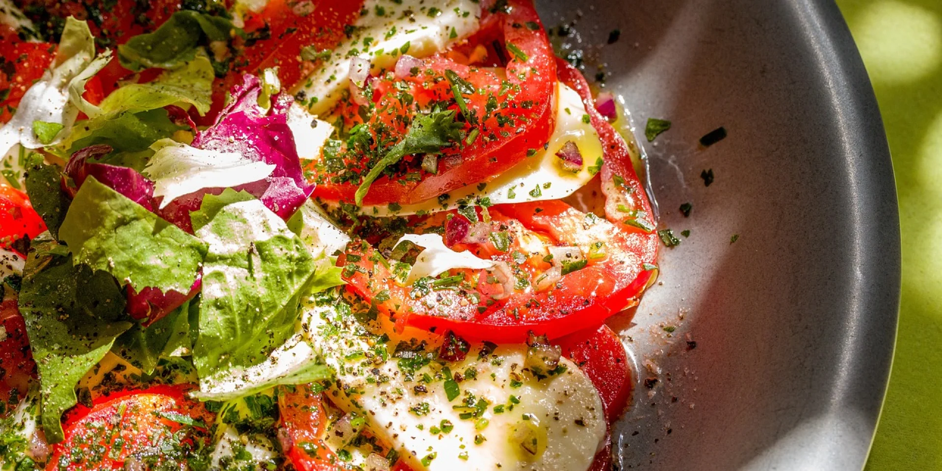 Assiette de salade végétarienne avec des feuilles de salade coupées, des tomates, des herbes, de l'huile d'olive