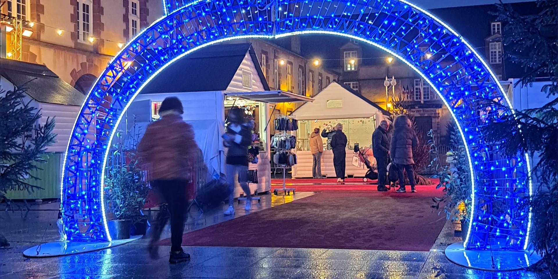 Illuminations sous forme de boule de Noël sous laquelle une personne passe, à l'entrée du marché de Noël de Rodez