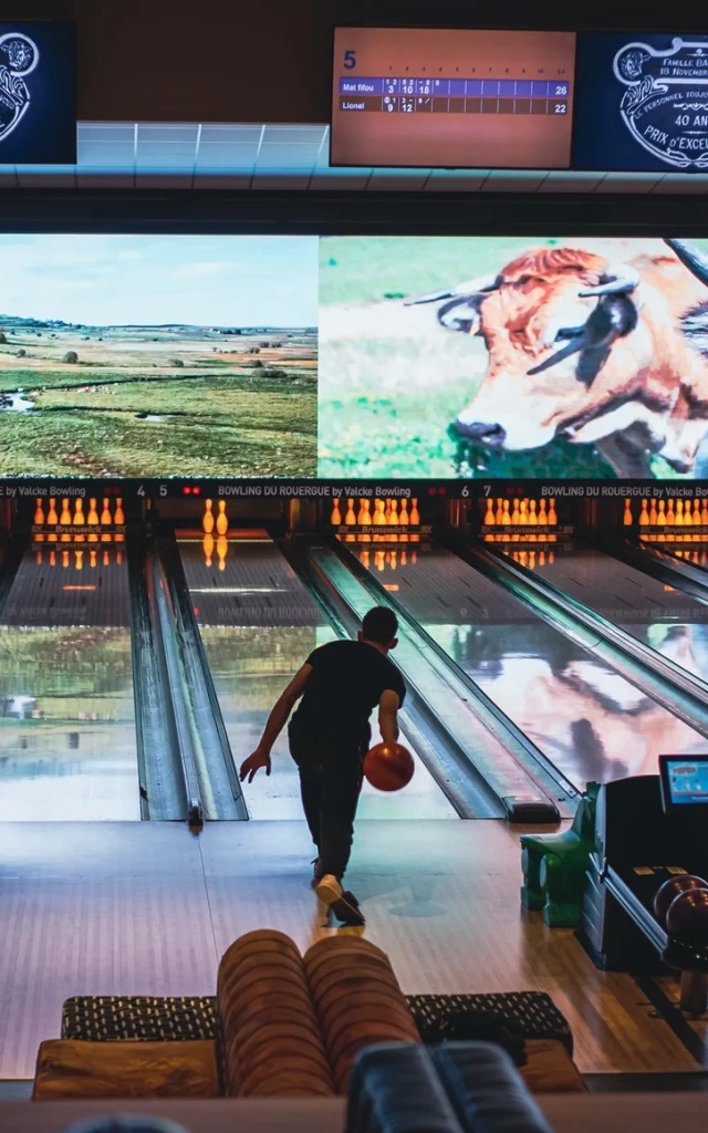 Personne lançant une boule de bowling sur la piste, vers les quilles