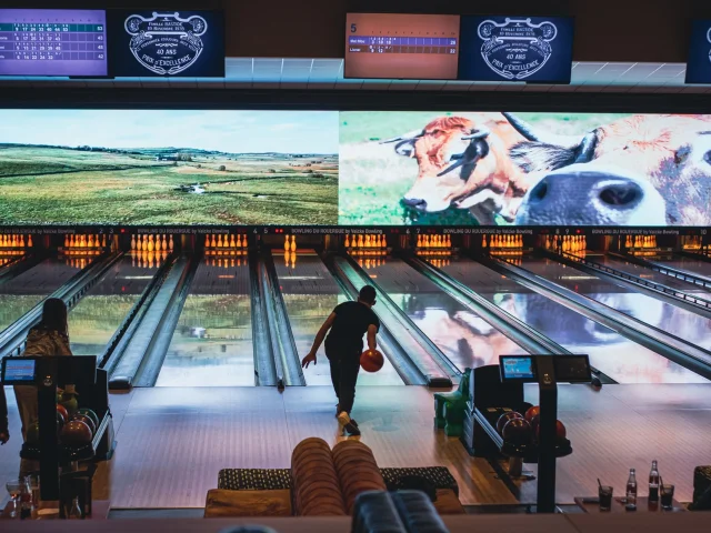 Personne lançant une boule de bowling sur la piste, vers les quilles