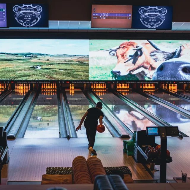 Personne lançant une boule de bowling sur la piste, vers les quilles