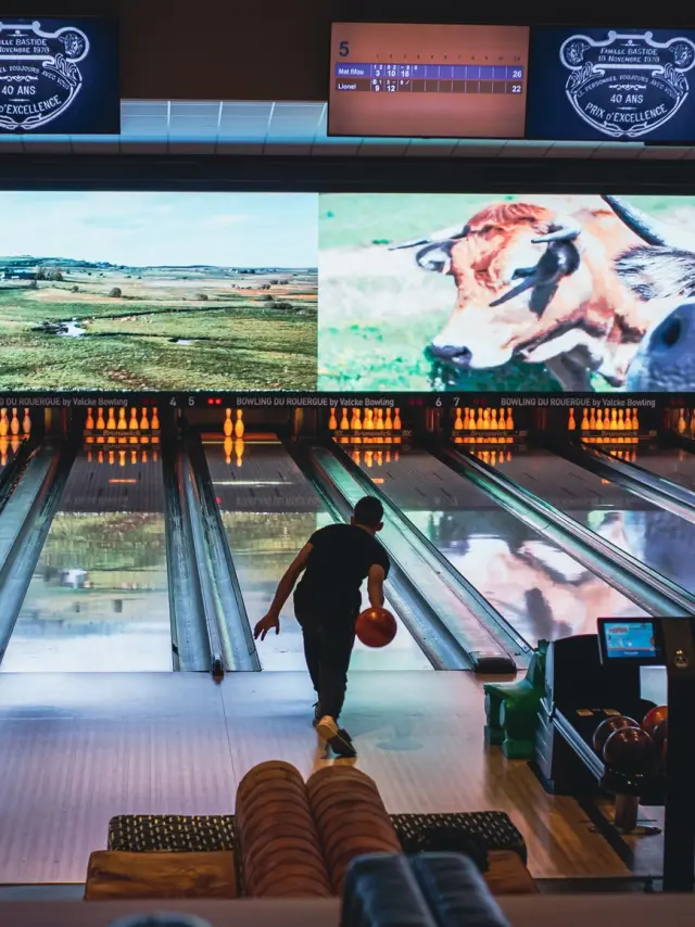 Personne lançant une boule de bowling sur la piste, vers les quilles