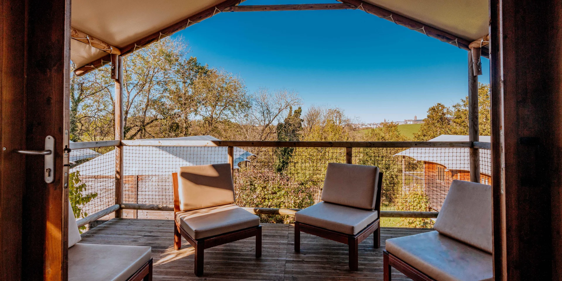 Terrasse d'un chalet avec des fauteuils au Domaine de Combelles, avec vue sur la cathédrale de Rodez