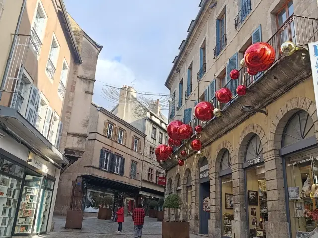 Boules rouges de Noël décoratives suspendues à la devanture de la boutique Bastide, en centre ville de Rodez