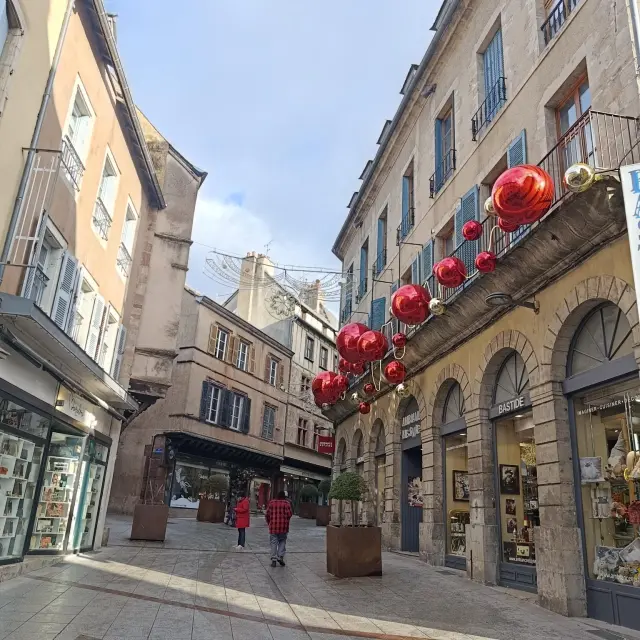 Boules rouges de Noël décoratives suspendues à la devanture de la boutique Bastide, en centre ville de Rodez