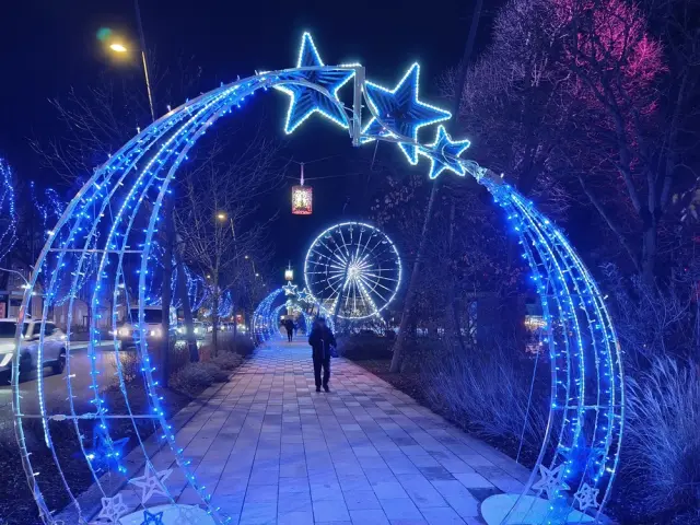 Arches de Noël illuminées en bleu sur l'allée piétonne Victor-Hugo vue de nuit, avec la grande roue en fond de paysage