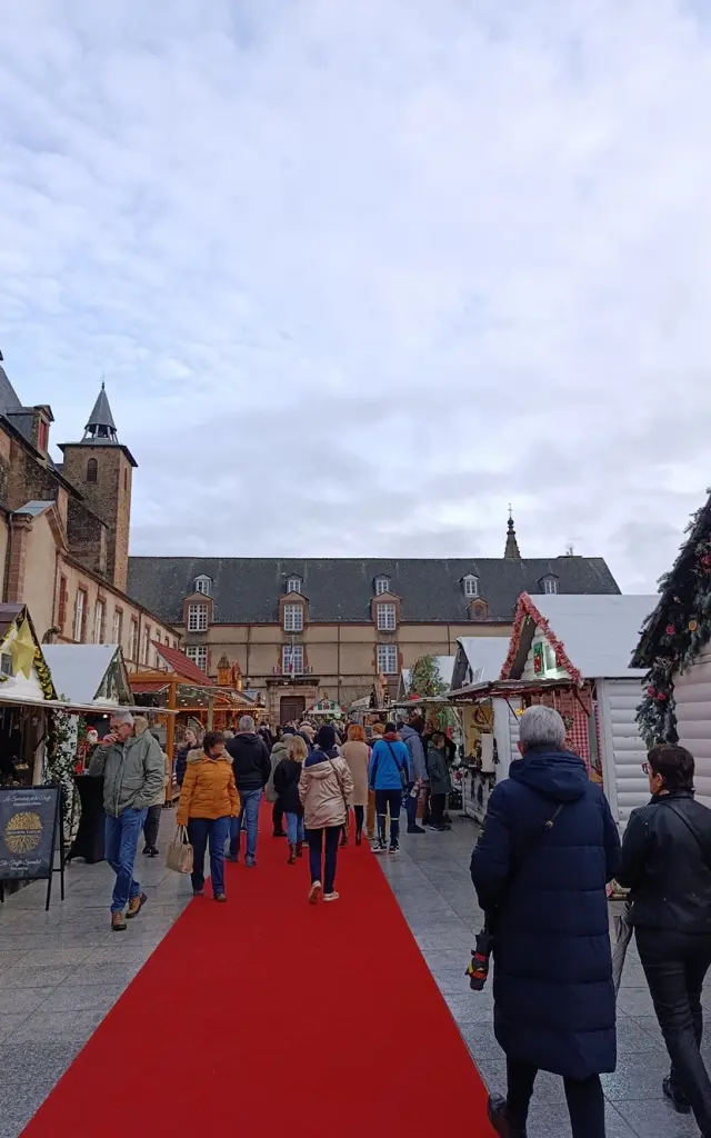 Foule de personnes entre les chalets en bois du marché de Noël de Rodez