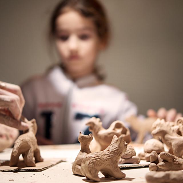 girl molds a seal from the clay, the teacher helps her. Blurred Background