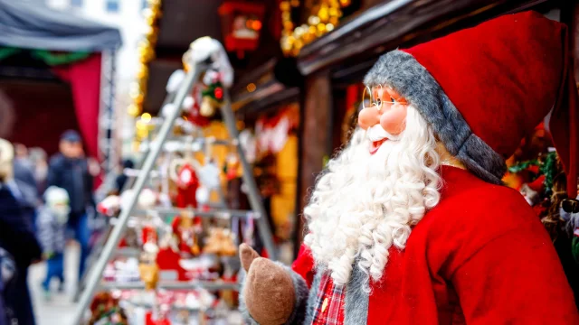 christmas market in Germany cute Santa Clause called Weihnachtsmann in German decoration, gifts, Xmas tree balls and illumination for sale.