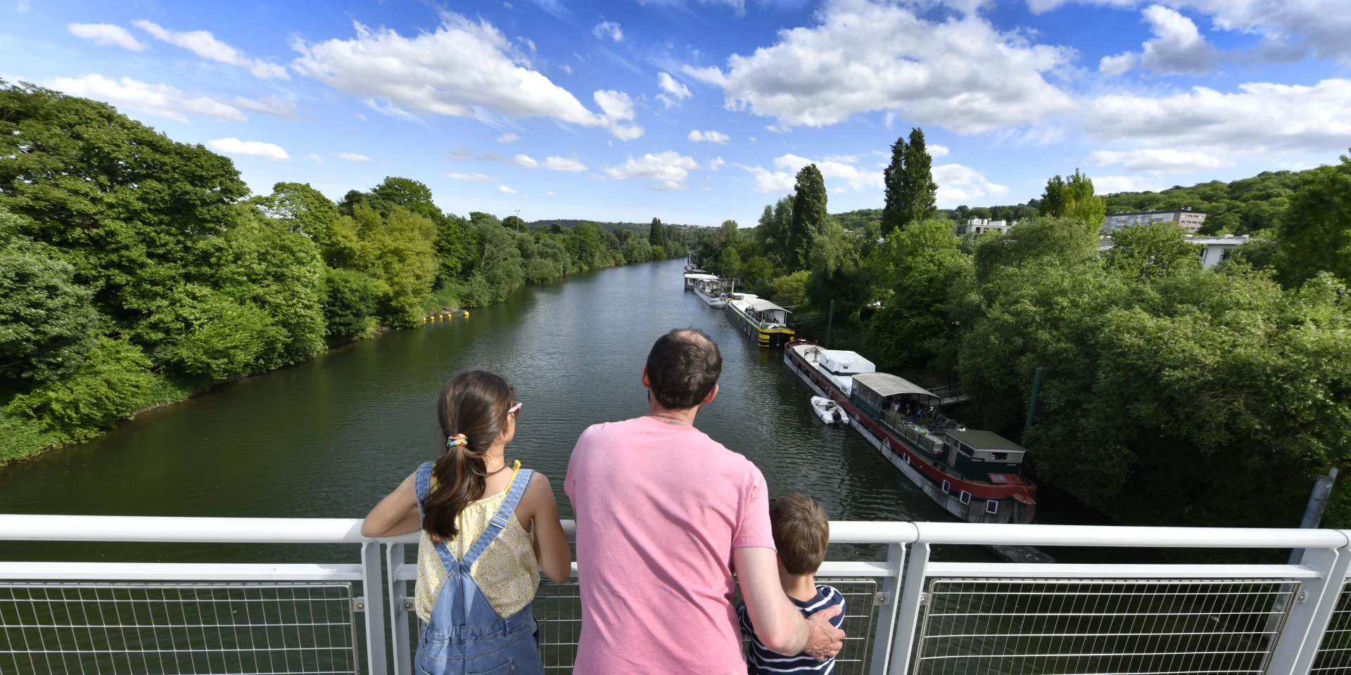 Un adulte et deux enfants entrain de regarder la Seine. Vue depuis la passerelle du Port-Marly