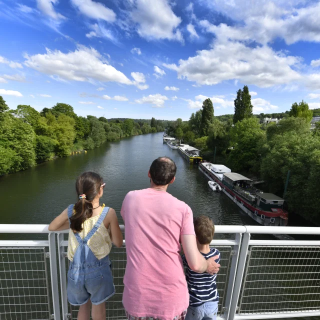 Un adulte et deux enfants entrain de regarder la Seine. Vue depuis la passerelle du Port-Marly