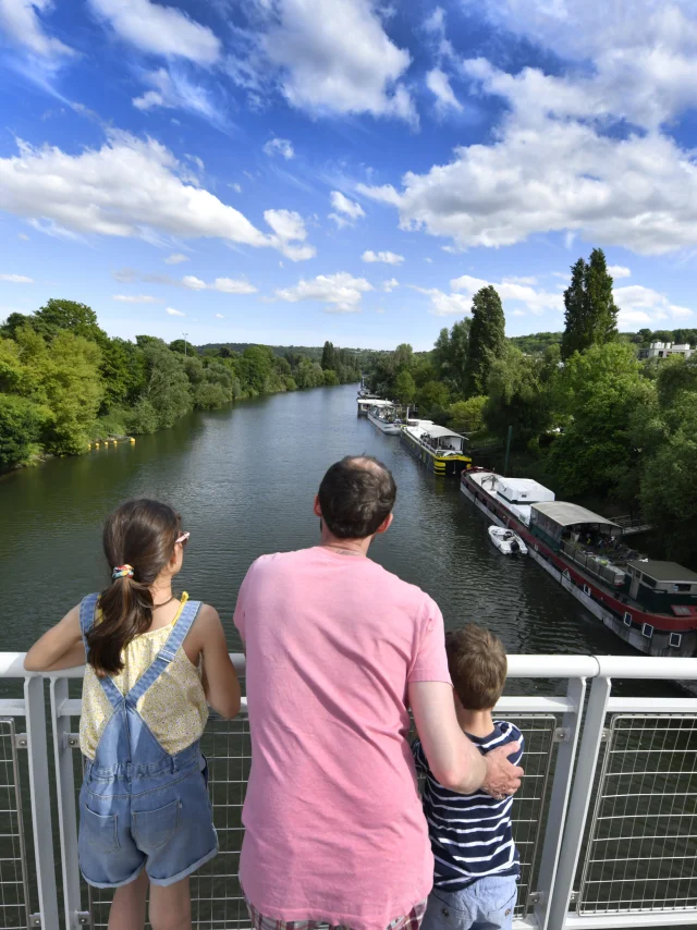 Un adulte et deux enfants entrain de regarder la Seine. Vue depuis la passerelle du Port-Marly