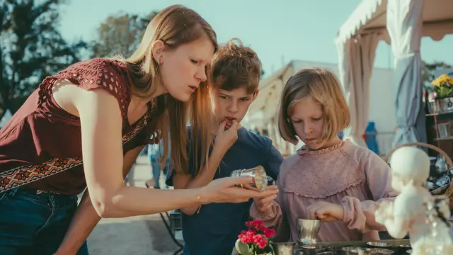 Une mère expliquant ces deux enfants un objet trouvé sur un stand de la foire de Chatou