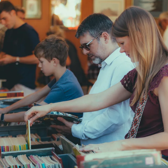 Deux adultes et un enfant regardant les vinyles à la foire de Chatou
