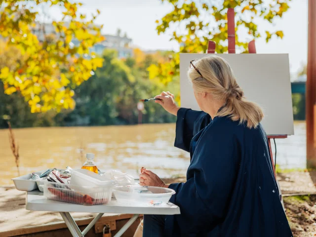 Femme entrain de peindre sur une toile en bords de Seine