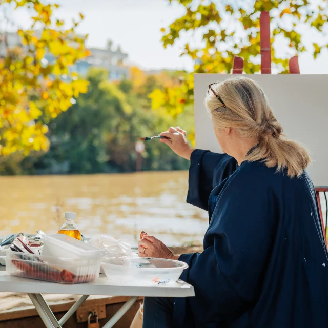 Femme entrain de peindre sur une toile en bords de Seine