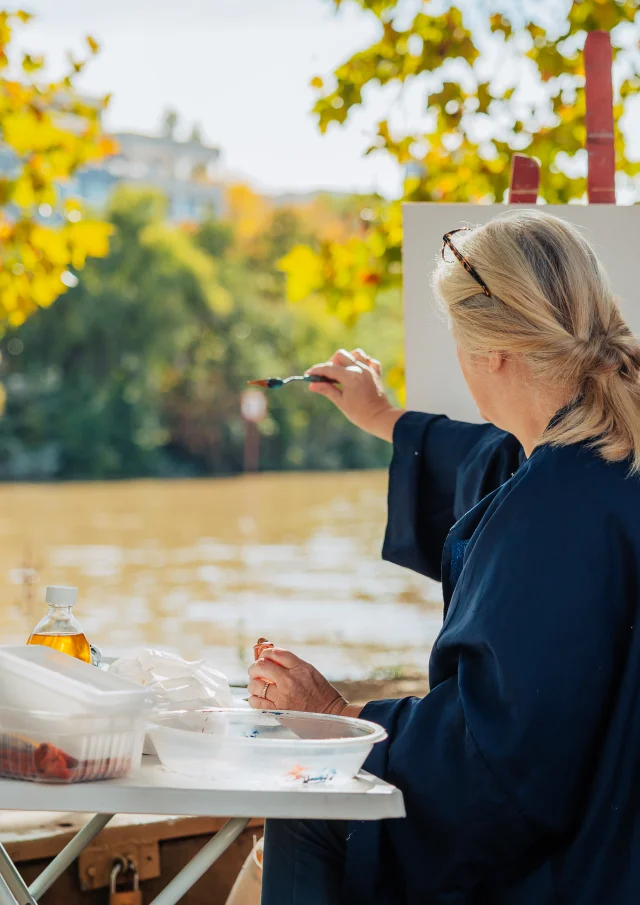 Femme entrain de peindre sur une toile en bords de Seine