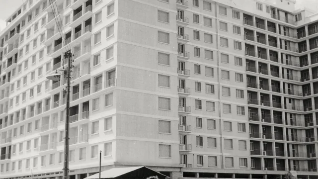 Une femme pose devant le Building en construction à Saint-Nazaire vers 1953.