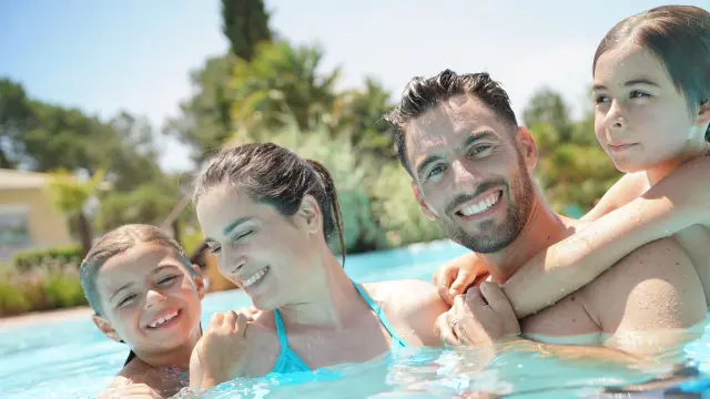 Portrait of happy family at the swimming-pool in summer